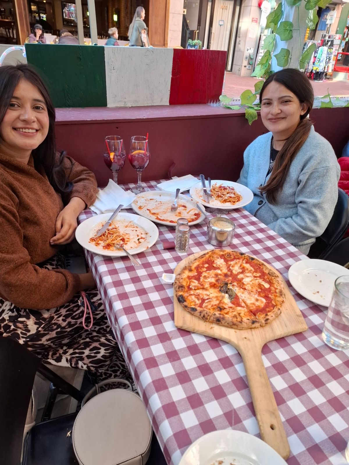 Two diners enjoying pizza and pasta together at a checkered table