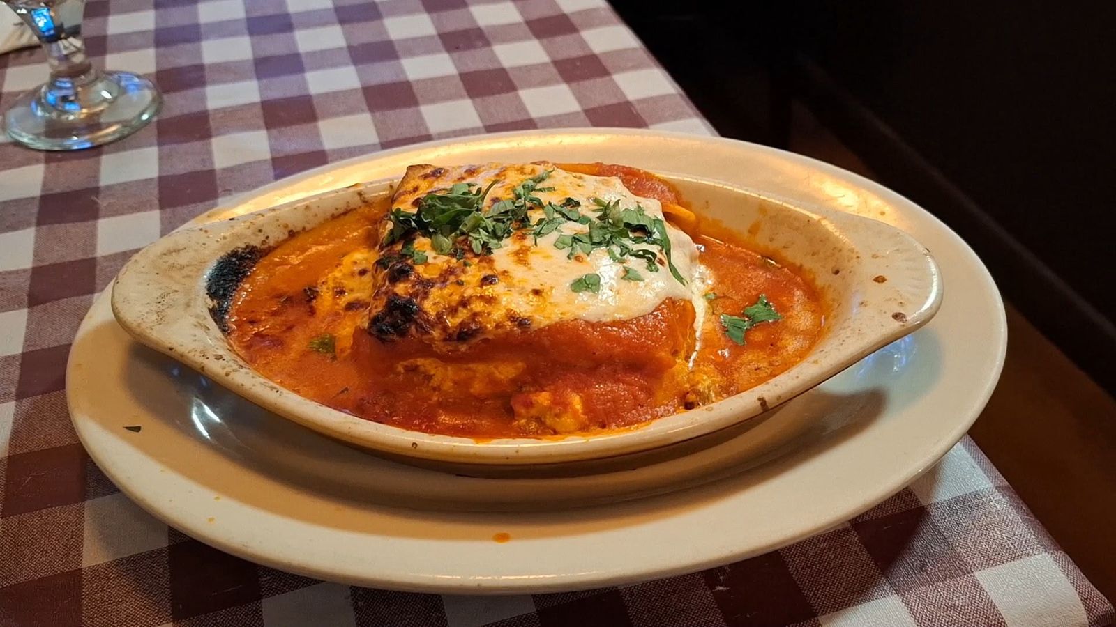 Close-up of a plated Italian dish topped with melted cheese and tomato sauce